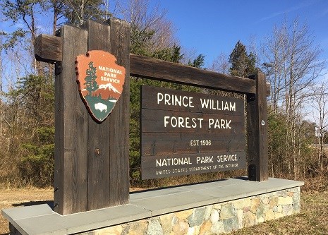 Large wooden sign wit a stone base at the entrance of Prince William Forest Park