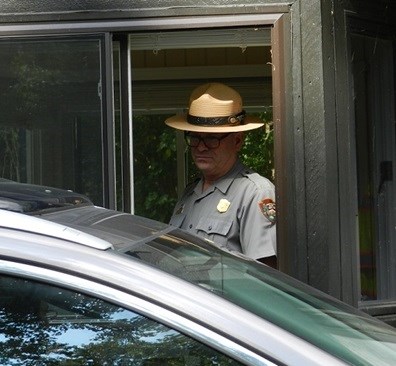 Park ranger collecting entrance fees at a window of a small wooden building