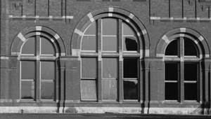 Three brick arches housing windows.
