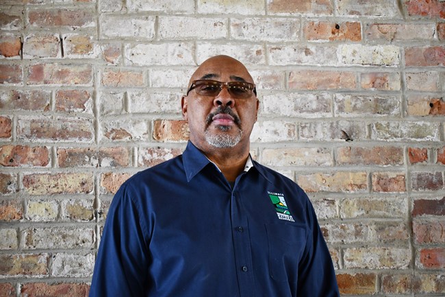 A man wearing glasses wears a navy blue polo with the Illinois Department of Natural Resources logo.