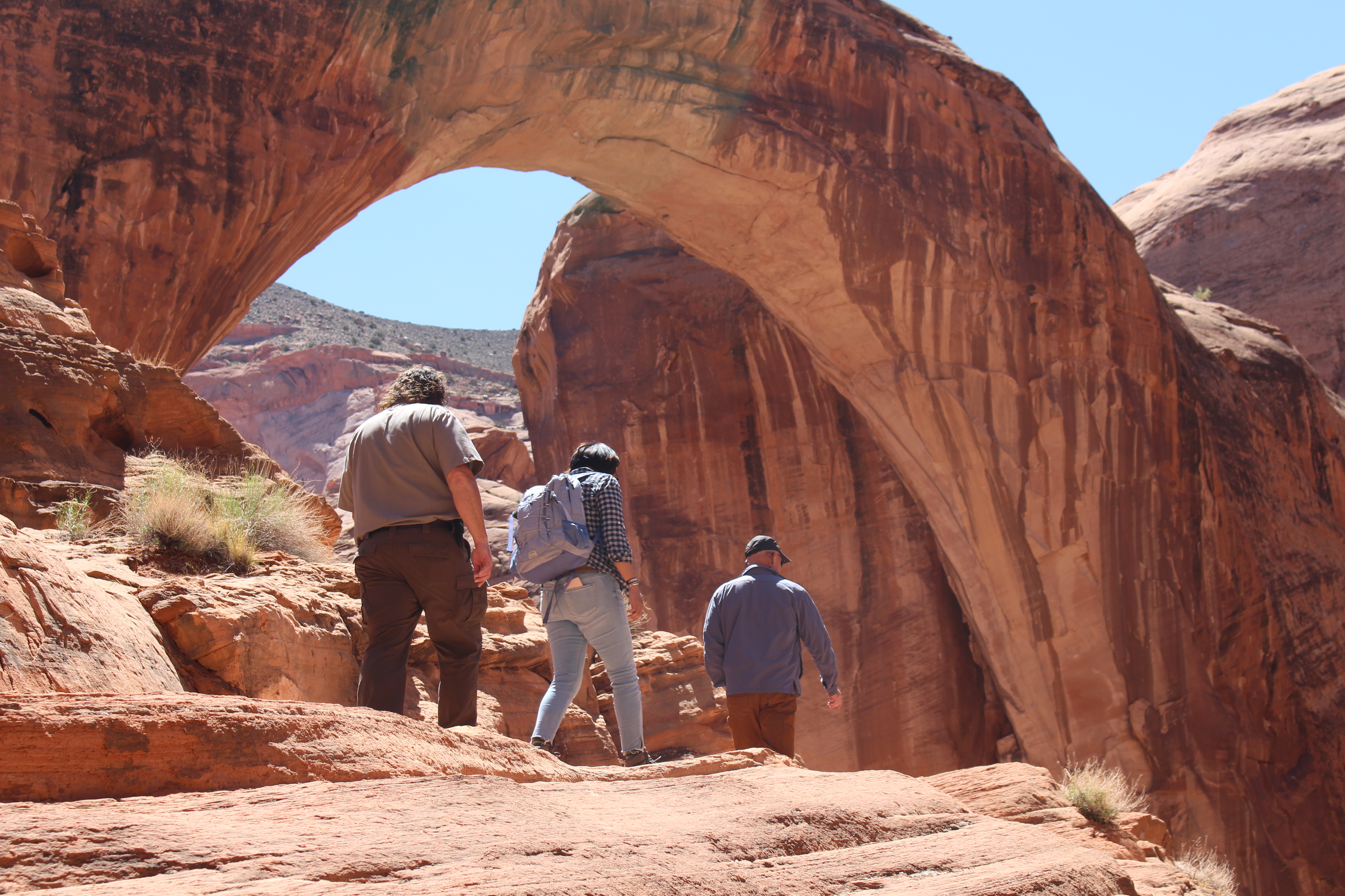 Three people walk on a sandstone outcrop.
