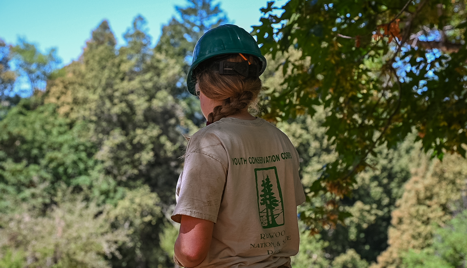 YCC participant, facing away from camera, with hard hat and YCC shirt on.