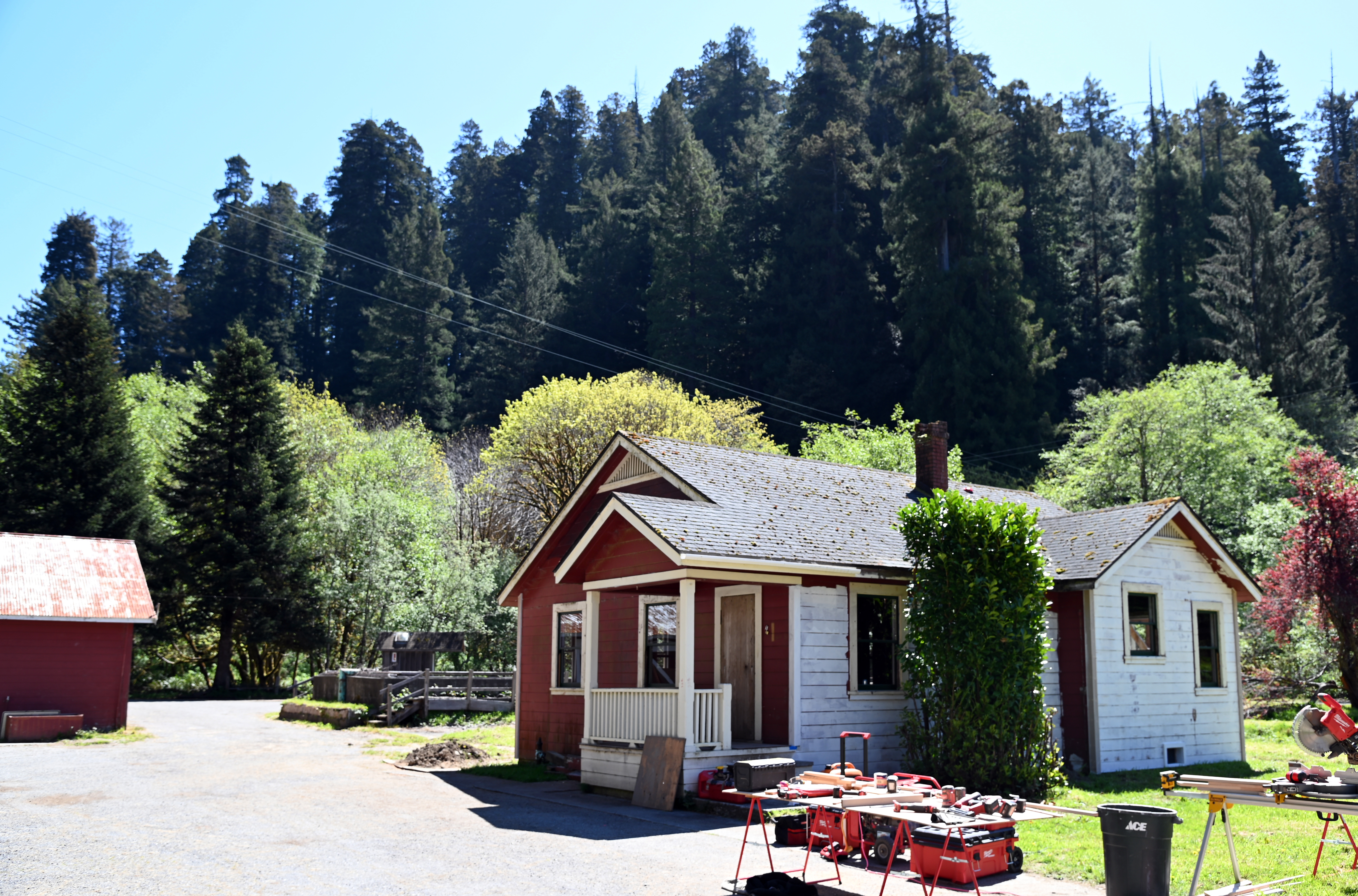 A single story building being worked on. Trees surround the area.