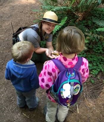 A ranger crouches down to chat with children