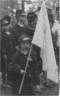 Little girl dressed in Civil War uniform jacket carries a white flag.