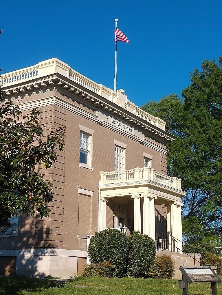 A gray brick building with an American flag flying from a flagpole on the roof.