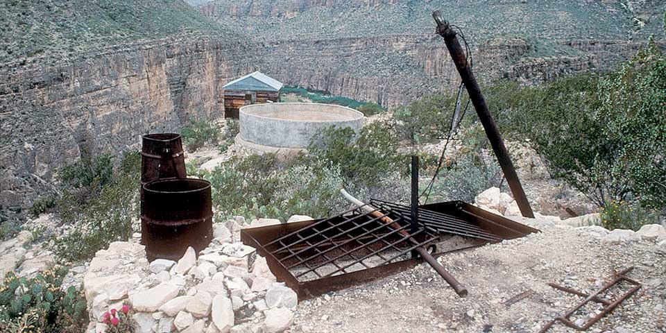 Rusted metal barrels and other equipment are all that remain of a remote desert pump.