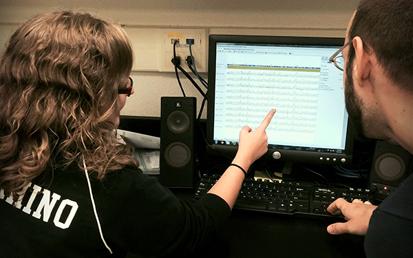 Two students look at a spreadsheet on a computer screen.