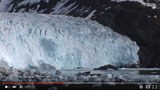 Still-frame of a video; the end of a glacier at the sea.