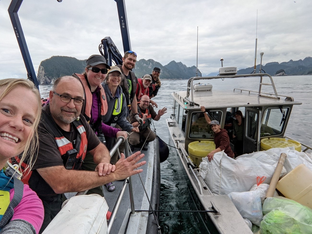 A group of people smile on a boat after a beach cleanup.