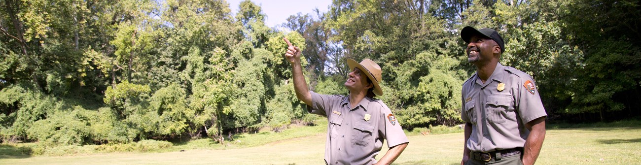 Two rangers smile and point at the sky