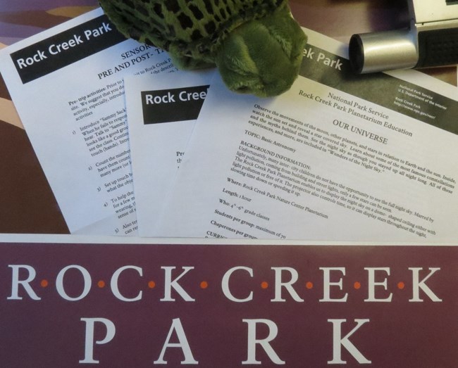 A turtle, lesson plans and Rock Creek Park logo spread on a table