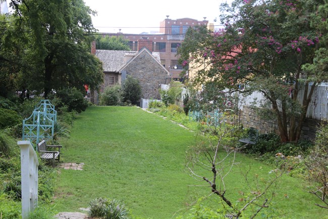 A landscaped garden with green grass and plants precedes an old stone building