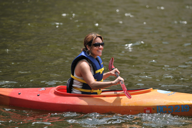 A smiling woman is kayaking on a river