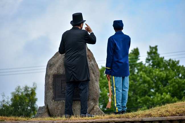 a Lincoln reenactor showing a young visitor the landscape at fort stevens