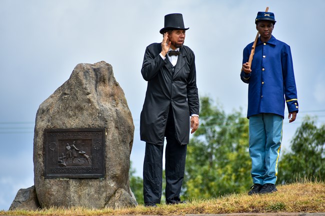 An Abraham Lincoln and Civil War soldier reenactors stand on top of a fort