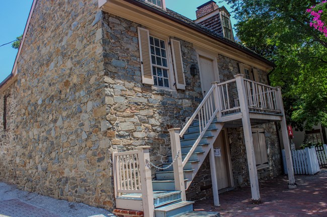 A building made of stone sits along a street with a brick sidewalk.