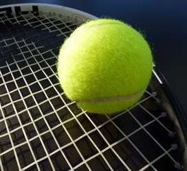 A generic tennis ball resting on a tennis racket.