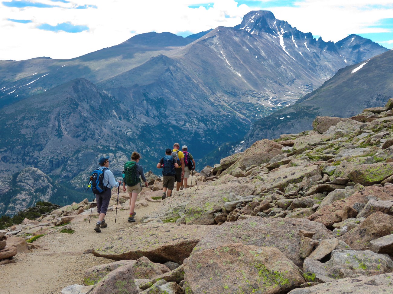 A group of four people are hiking up a mountain trail in RMNP.