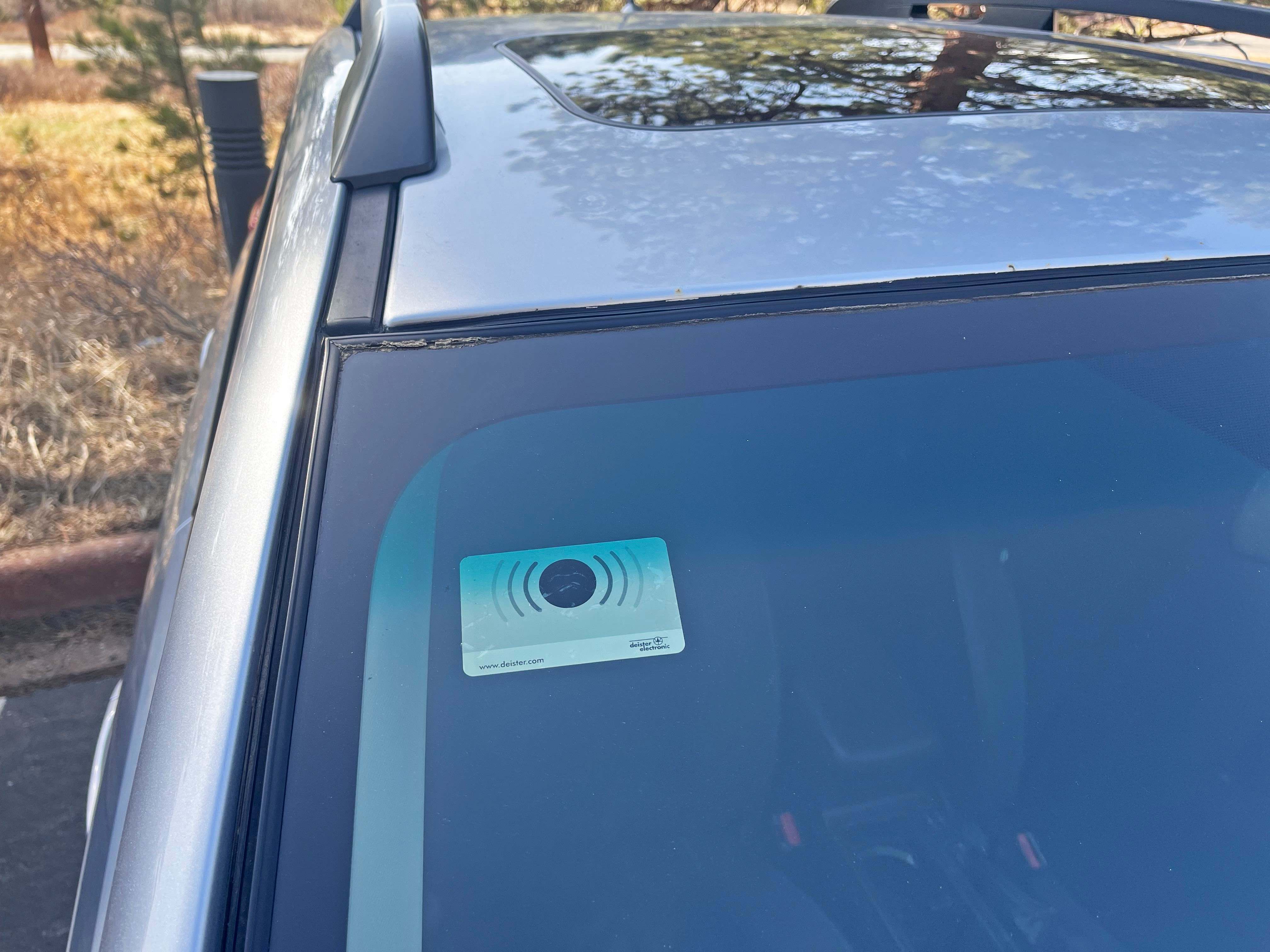 A credit-card sized device has been placed on the inside of a passenger vehicle's windshield. The device is affixed on the top right-hand side.  