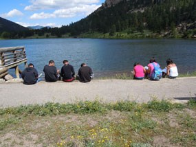 Students sitting on the edge of Lily Lake.