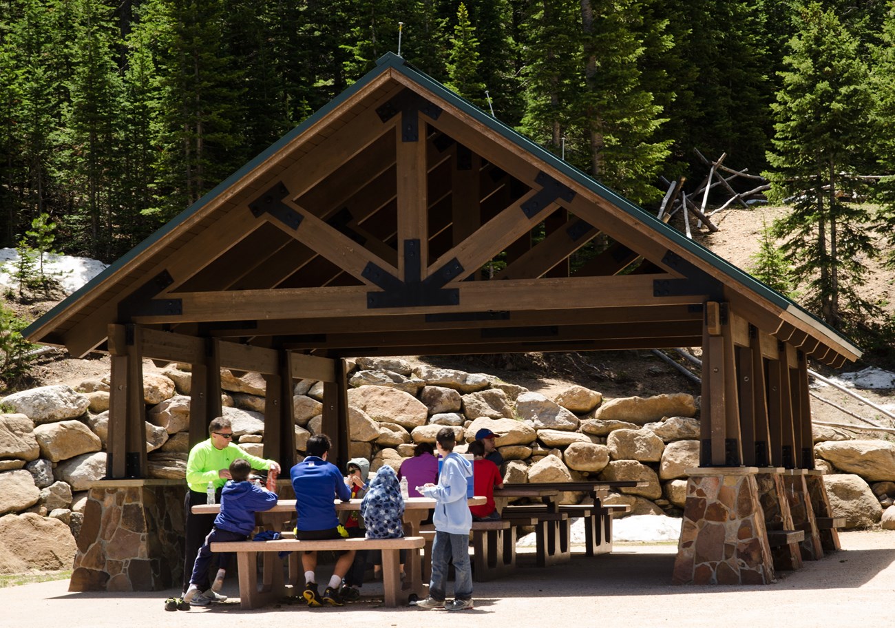 A group of people are sitting at tables and having a picnic at the Hidden Valley Picnic Pavilion