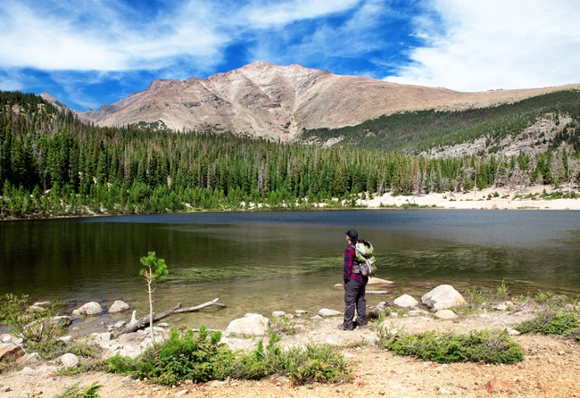 Hiking standing at the shore of an alpine lake