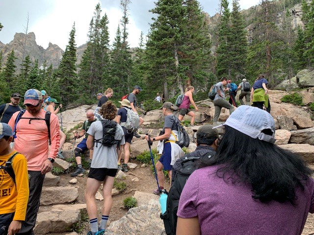 Hikers are seen going uphill and downhill on a crowded trail during summer in RMNP