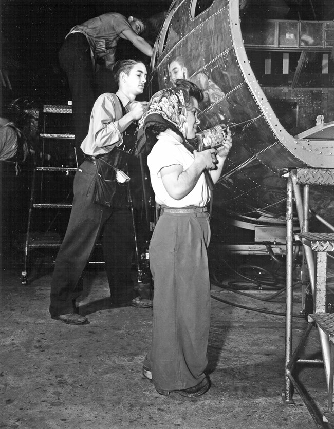 A young man and a Little person "Rosie" work on an airplane.