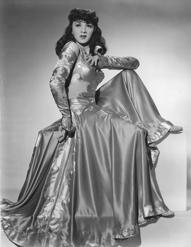 Asian man dressed in drag in an elegant gown. Posing for photo. Historic photo.