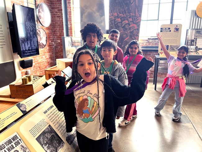 A group of kids stand in front of a park exhibit.