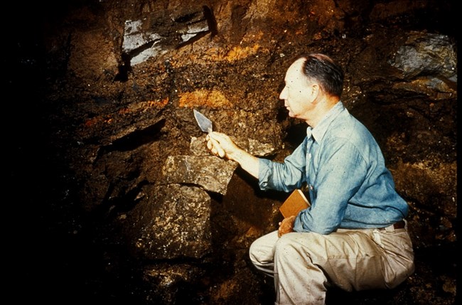 Carl Miller holding a trowel sitting in an excavated pit