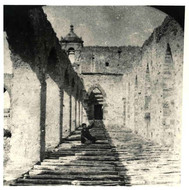 Young boy on second floor of historic structure, church tower pictured in the back