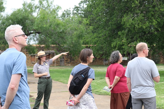 Female Park Ranger points as she leads a tour through Mission San Jose.