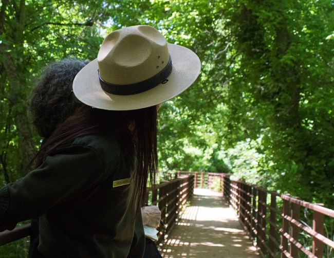 Park Ranger looks down the Yanaguana Trail, where a wooden boardwalk takes visitors along the San Antonio River