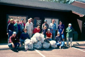 A group of people stand in front of the Trego Visitor Center with bags of trash