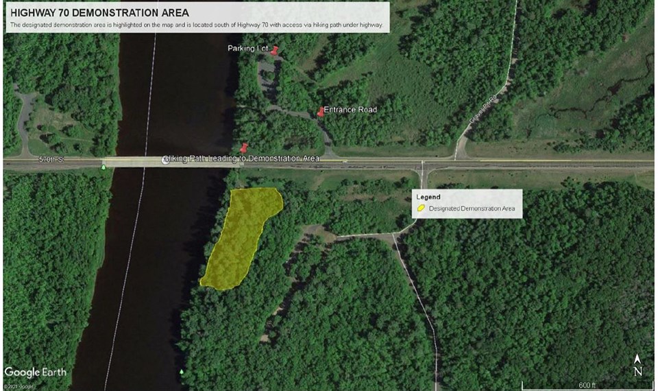 Aerial map image of a green forest with a river flowing through. White lettering next to red thumbtacks over the tops of green trees.