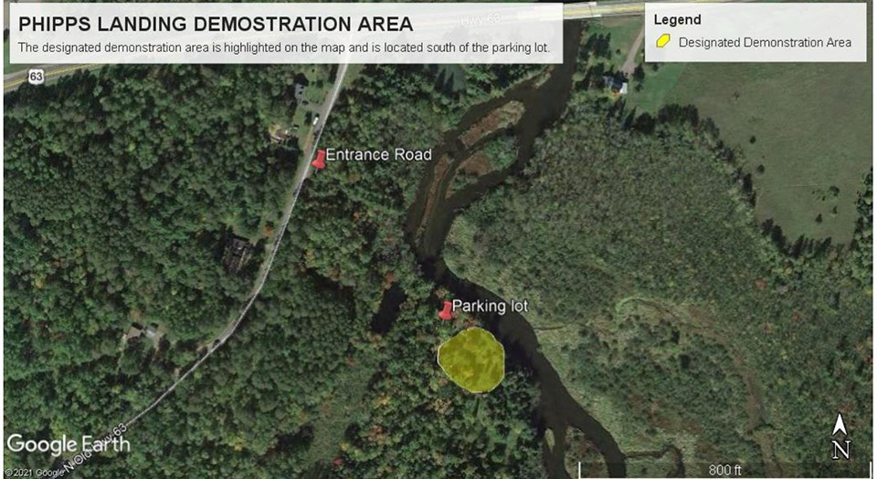 Aerial map image of a green forest with a river flowing through the middle. White lettering next to red thumbtacks over the tops of green trees.