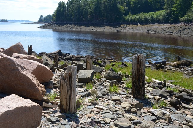 Wooden support beams stick out of Red Beach during low tide.