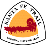 Rounded triangular graphic with red covered wagon pulled by six oxen against a yellow background, surrounded by white band containing the text, "Santa Fe Trail National Historic Trail"