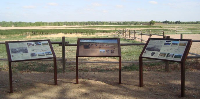three wayside exhibit panels in front of a view of wood rail fences crossing an open prairie