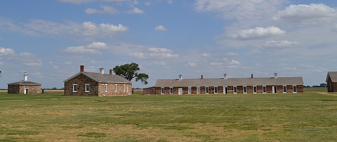 grass in the foreground, brick building farther back, blue sky