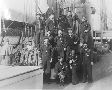Sailors standing on the deck of a sailing ship.