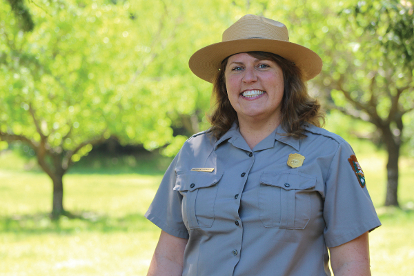 Chief of Cultural Resources Gretchen Stromberg wearing a NPS uniform, standing outside with trees in the background