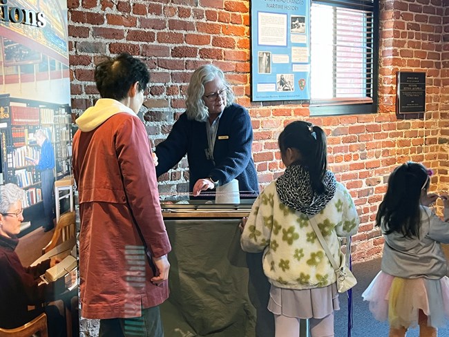 A volunteer demonstrates rope-making techniques to a family.