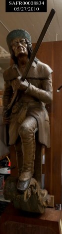 Photograph of dark wood carved figurehead of David Crockett with musket
