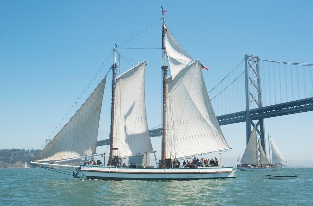 the ship Alma sails on the San Francisco Bay with the Bay Bridge visible in the background