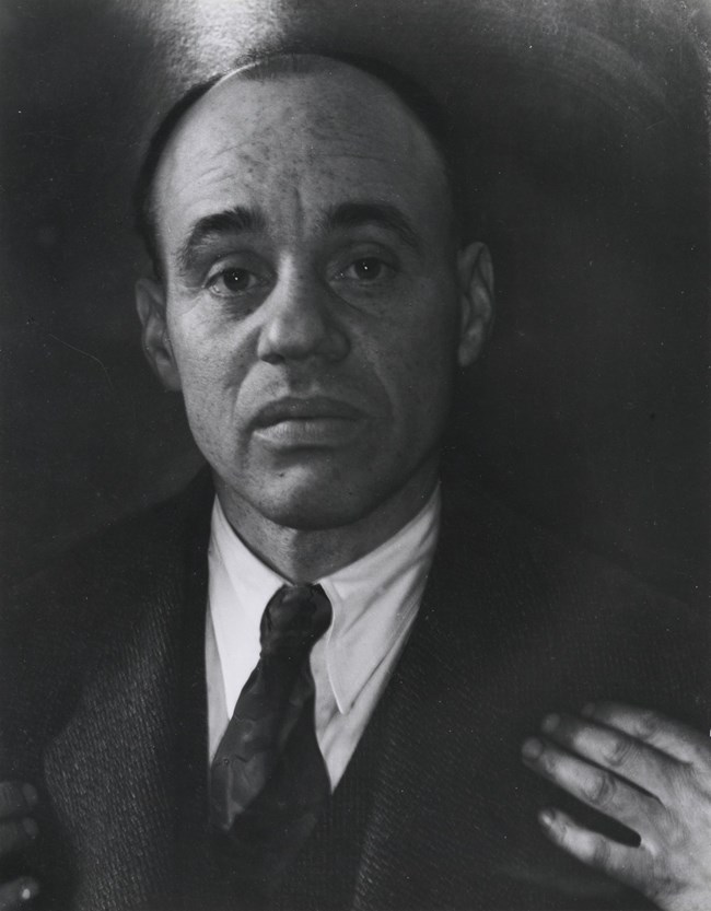 black and white photo of Sargent Johnson as he looks directly into the camera