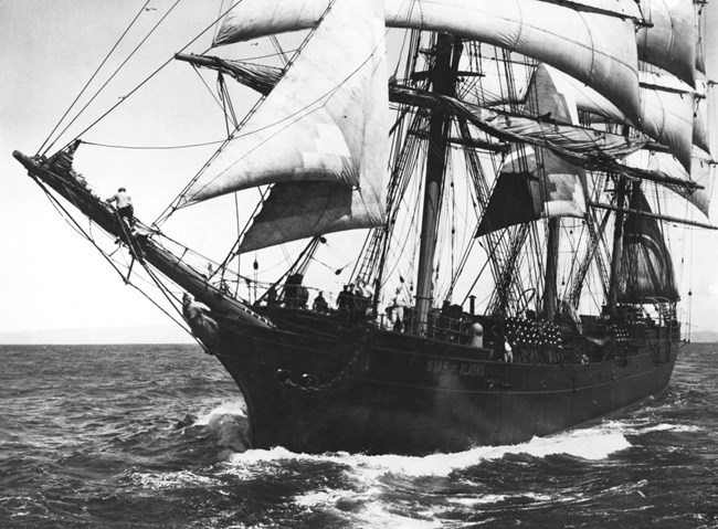 historical photograph of a large sailing ship on sailing on the water. The ship bears the name "Star of Alaska" on the bow of the hull.