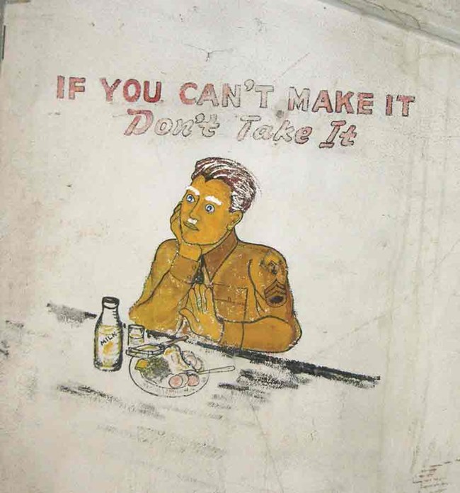 Mural painted on a plaster wall depicing a solider in a World War II uniform eating meal.